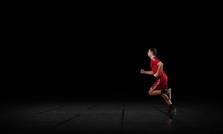 Running man in red sport wear on black backgroundの写真素材