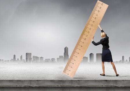 Young businesswoman measuring something with big rulerの写真素材