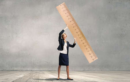 Young businesswoman measuring something with big rulerの写真素材