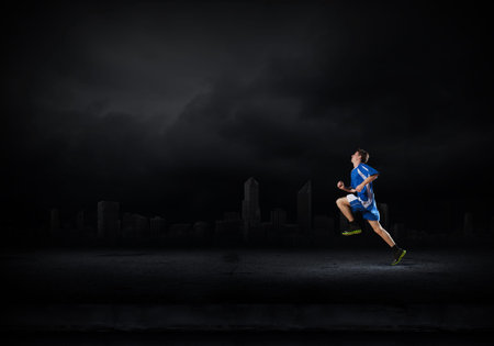 Running man in blue sport wear on black backgroundの写真素材