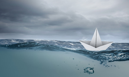 Paper ship floating on water on stormy wavesの写真素材