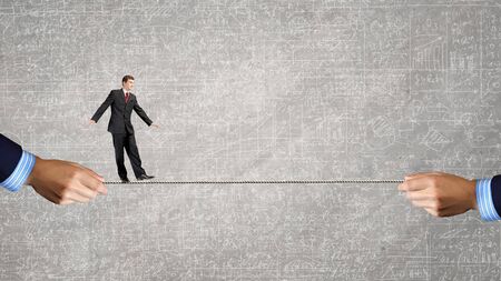 Young brave ricky businessman balancing on ropeの写真素材