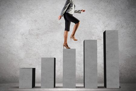 Young businesswoman stepping up on chart barの写真素材