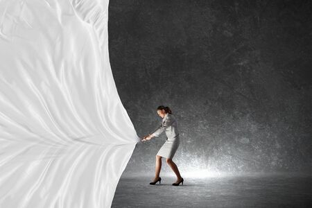 Young pretty businesswoman pulling clothing blank bannerの写真素材