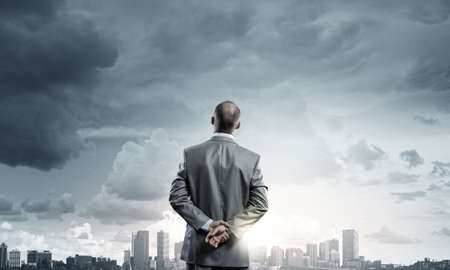 Businessman stands back and looks at flying objectsの写真素材
