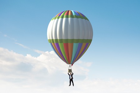 Businessman flying in search of ideas hanging on balloonの写真素材