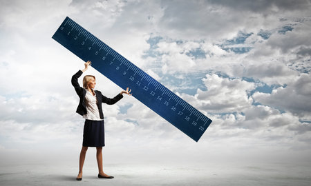 Young businesswoman measuring something with big ruler