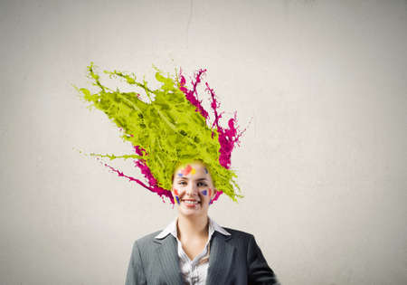 Thoughtful businesswoman with colorful splashes out of his headの写真素材