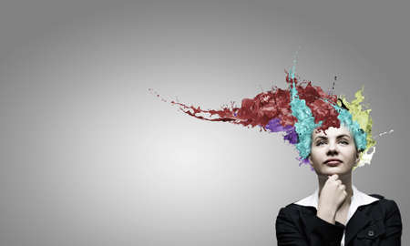 Thoughtful businesswoman with colorful splashes out of his headの写真素材