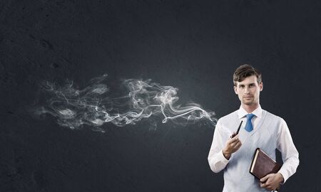 Handsome young businessman thinking over ideas and smoking pipeの写真素材