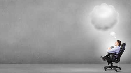 Confident handsome businessman sitting in chair and dreamingの写真素材