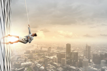 Concept of competition with businesswoman climbing office building with rope