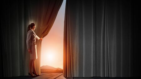 Young woman in business suit opening color curtain of stageの写真素材