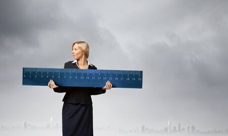 Young businesswoman measuring something with big rulerの写真素材