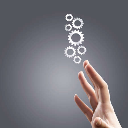 Close up human hand pointing at gears mechanismの写真素材