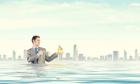 Funny businessman with yellow rubber duck toyの写真素材