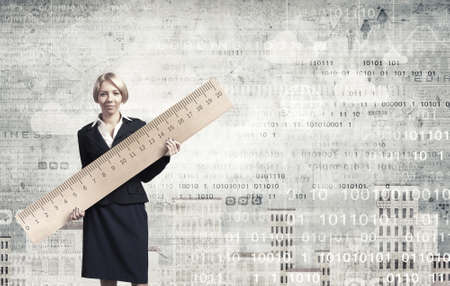 Young businesswoman measuring something with big rulerの写真素材
