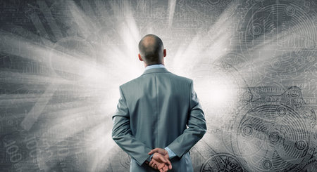 Businessman stands back and looks at flying objectsの写真素材