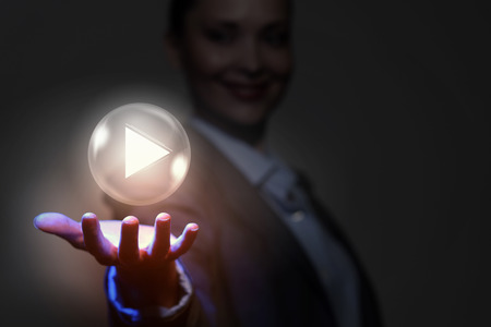 Businesswoman with media player button in palmの写真素材