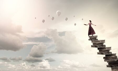 Woman in long dress with blindfold on eyes and book in handの写真素材