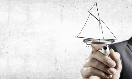 Close up of businessman hand drawing yacht with markerの写真素材