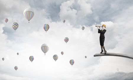 Young woman engineer on top looking in spyglassの写真素材