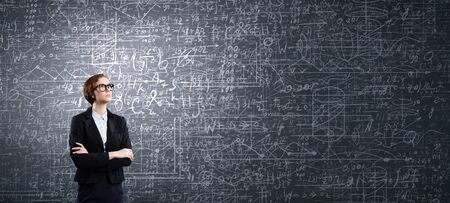 Young confident woman wearing glasses standing near blackboardの写真素材