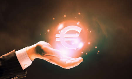 Close up of human hand holding golden euro symbolの写真素材