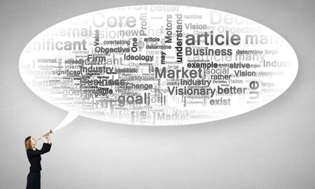 Young businesswoman in suit proclaiming something in hornの写真素材