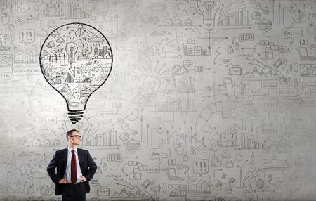 Young confident man wearing glasses standing near blackboardの写真素材