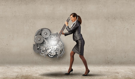 Young businesswoman fixing gears mechanism with wrenchの写真素材