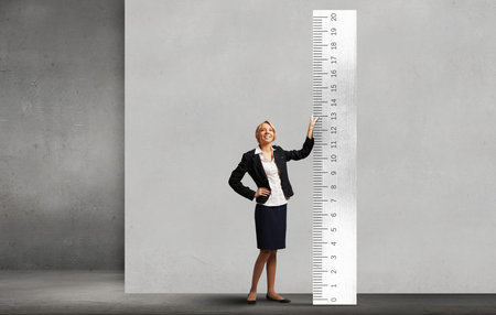 Young businesswoman measuring something with big ruler