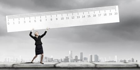Young businesswoman measuring something with big rulerの写真素材