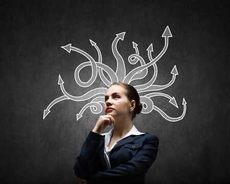 Thoughtful businesswoman with arrows and thoughts coming out of her headの写真素材