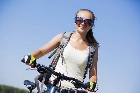 Young beautiful woman riding a bicycle in a parkの写真素材