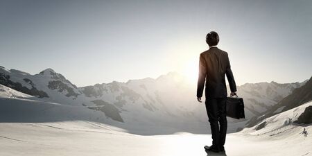Rear view of businessman look at sunrise above mountainの写真素材