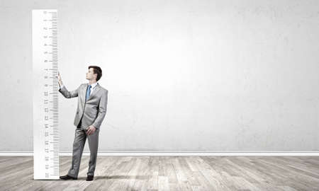 Young businessman in suit measuring ruler benefitの写真素材
