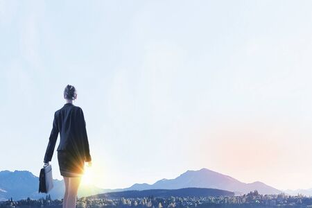 Rear view of businesswoman look at sunrise above mountainの写真素材