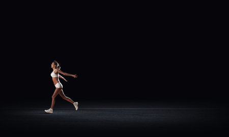 Running woman in sport wear on black backgroundの写真素材