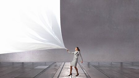 Young pretty businesswoman pulling clothing blank bannerの写真素材
