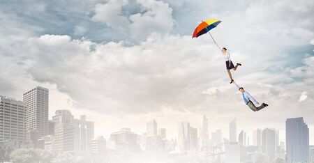 Business people flying in the sky on umbrellaの写真素材