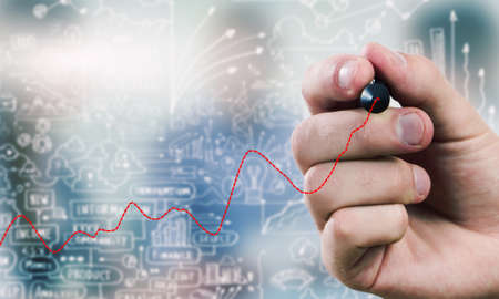 Close up of businessman drawing increasing graph with marker on media screenの写真素材