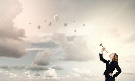 Young businesswoman in suit proclaiming something in hornの写真素材