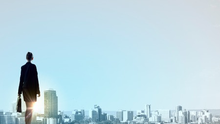 Rear view of businesswoman look at sunrise above cityの写真素材