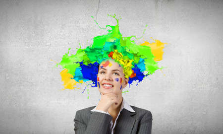 Thoughtful businesswoman with colorful splashes out of his headの写真素材