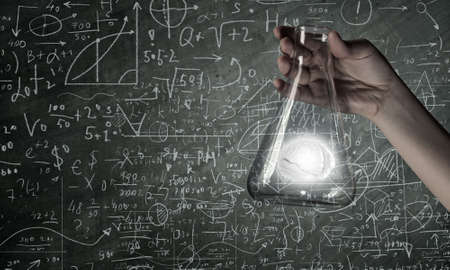 Hand holds flask with images on varied backgroundの写真素材