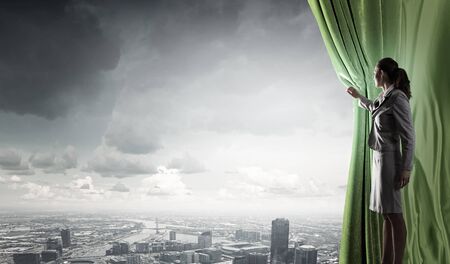 Young businesswoman opening stage curtain to another realityの写真素材