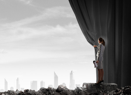 Young businesswoman opening stage curtain to another realityの写真素材
