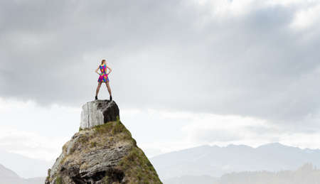 Young girl in multicolored bright dress on rock topの写真素材