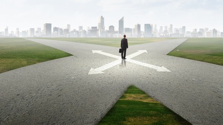 Back view of businessman standing at crossroads and making choiceの写真素材